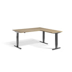 Lavoro Advance Corner triple-motor standing desk, dark grey frame and natural oak desktop; pictured size representative